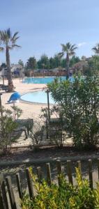 una piscina con una panchina e un ombrellone di Mobil home Oasis Les Palmiers a Valras-Plage