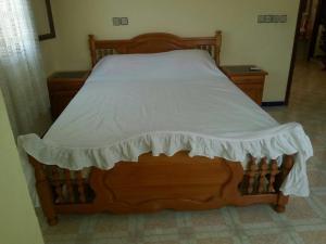 a bedroom with a wooden bed with a white bedspread at Appartement bni bouayache in Aït Farts