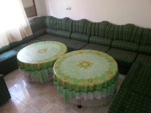 a green couch with two tables in a living room at Appartement bni bouayache in Aït Farts