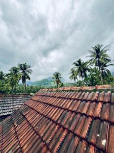 an old rusty roof with palm trees in the background at HARSHAM Eco Village in Puthuppādi