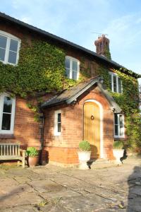 a brick house with a wooden door and a bench at The Jockey Room Hideaway in Spurstow