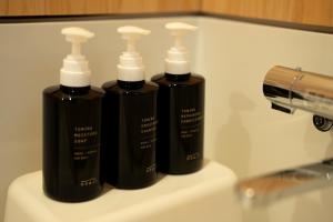 three black bottles sitting on top of a sink at Rotan寺町 in Matsue
