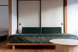 a bedroom with a green bed and a white table at Rotan寺町 in Matsue