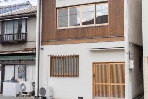 a white building with wooden windows and a balcony at Rotan寺町 in Matsue