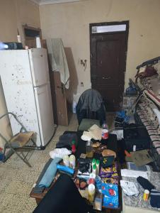 een rommelige kamer met een koelkast en een tafel bij Ben jeddi in M'diq
