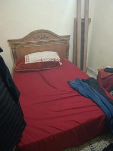 een rood bed met een houten hoofdeinde en een rode deken bij Ben jeddi in M'diq