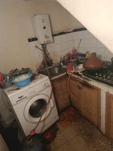 een vieze keuken met een wasmachine en een gootsteen bij Ben jeddi in M'diq
