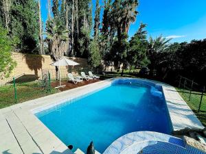 a large blue swimming pool in a yard with trees at Shangri la - Casa y Pileta Privada in Mendoza