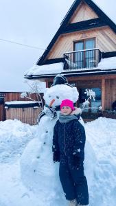 een jong kind dat naast een sneeuwpop staat bij Domek Fox House z prywatna balią elektryczną na wyłączność in Kościelisko