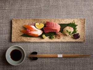 a plate of sushi with chopsticks and a cup of coffee at Glamday style hotel suite 川ノ音 in Kyū-karuisawa