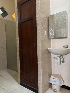 a bathroom with a wooden door and a sink at Rumah Cahaya Syariah Peaceful Family Home in Rampal +15 photos