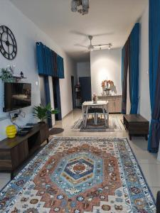 een woonkamer met een tafel en een tapijt bij Aiman's Rose HomeStay in Teluk Panglima Garang