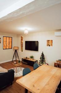 een woonkamer met een houten tafel en een tv bij Ancien Cloître rénové - Hyper centre - T2 de 50m2 in Mont-de-Marsan