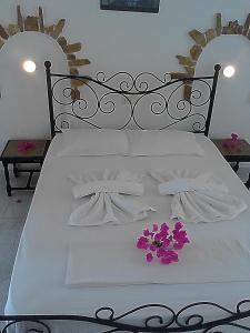 a white bed with white sheets and purple flowers on it at Angelika in Alinda