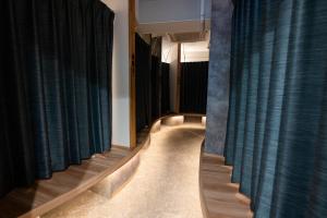 a room with blue curtains and a long hallway with wooden floors at Wa Hostel in Tokyo
