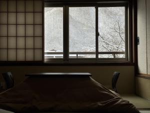 ein Fenster in einem Zimmer mit einem Bett davor in der Unterkunft Hirayukan in Takayama