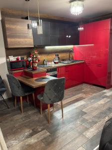 een keuken met rode kasten en een houten tafel bij Бутиков апартамент Kora DM in Stara Zagora