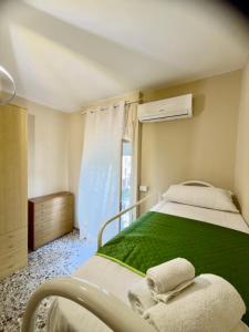 una camera da letto con un letto con lenzuola verdi e una finestra di Sperlonga Center Home a Sperlonga