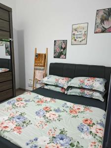 een bed met een bloemenbed en kussens erop bij Aiman's Rose HomeStay in Teluk Panglima Garang