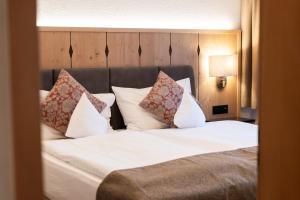 a bedroom with a bed with white sheets and pillows at Hotel Grindelwalderhof in Grindelwald