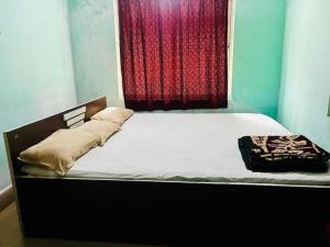 德奥加尔Alkapuri Guest House的卧室内的一张床位,配有红色窗帘 更多6张照片
