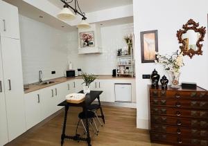 eine Küche mit weißen Schränken und einem Tisch und einer Spüle in der Unterkunft Estudio Vandelvira in Baeza