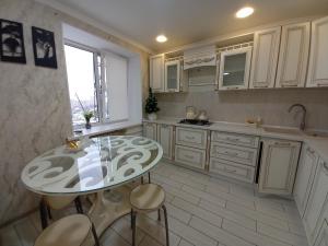 una cucina con tavolo, sedie e lavandino di Апартаменты в районе Космос ad Aqtöbe