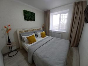 una camera da letto con un letto con cuscini gialli e una finestra di Апартаменты в районе Космос ad Aqtöbe