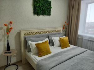 una camera da letto con un letto con cuscini gialli e bianchi di Апартаменты в районе Космос ad Aqtöbe Altre 12 foto