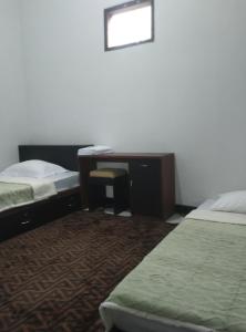 a hotel room with two beds and a desk at AN homestay2 Syariah in Wonosobo +3 photos