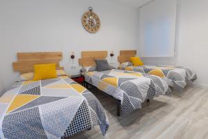 a group of beds in a room with a clock on the wall at Go-Vi Gozar en Vitoria in Vitoria-Gasteiz