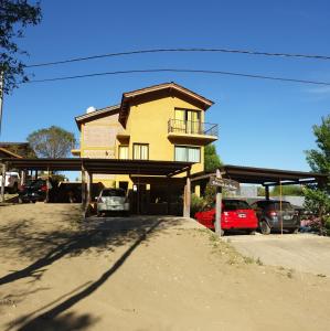 a yellow building with cars parked in a parking lot at Balcon de los Molles in Santa Rosa de Calamuchita