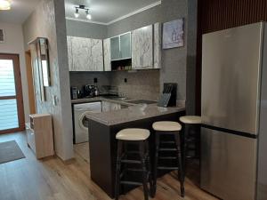 a kitchen with a refrigerator and bar with stools at Къща за гости Форест 58 in Vasil Levski