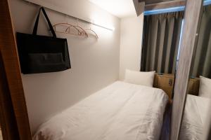 a small room with a bed and a bag on the wall at Wa Hostel in Tokyo