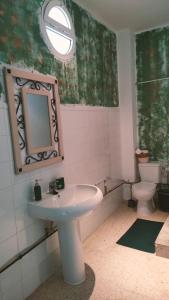 een badkamer met een wastafel, een toilet en een spiegel bij Las Brujas in Sanlúcar la Mayor