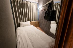 a small bedroom with a bed and a television at Wa Hostel in Tokyo