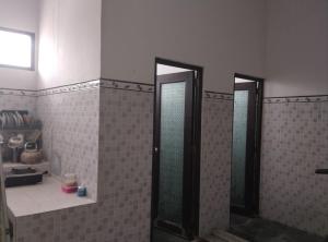 two mirrors in a bathroom with brown tiles at AN homestay2 Syariah in Wonosobo