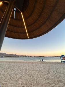 een strand met een rieten parasol en een strandstoel bij Azure in Aqaba