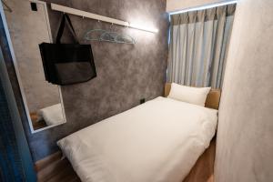 a small bedroom with a bed and a tv at Wa Hostel in Tokyo