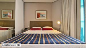 a bedroom with a large bed with two red pillows at Book Santos - Apartamentos no Unique Residence in Santos