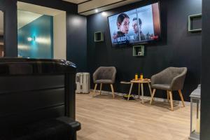 a waiting room with two chairs and a flat screen tv at Logement privatif avec Jaccuzi, sauna, Atdream in Bergues