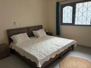 a bedroom with a bed with white sheets and a window at Maison indépendante avec jardin in Abidjan