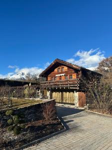 una grande casa in legno con montagne sullo sfondo di Chalet à Savièse en bordure de forêt a Savièse