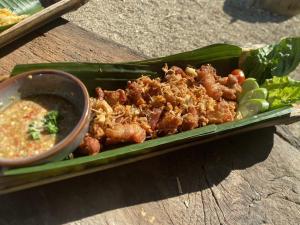 a plate of food with meat and a bowl of dipping sauce at Amazing Mountain Camping, Bar&Grill in Ban Pang Hai