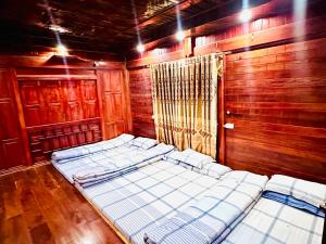 a room with four beds in it with wooden walls at Moc Chau Town - Homestay in Mộc Châu