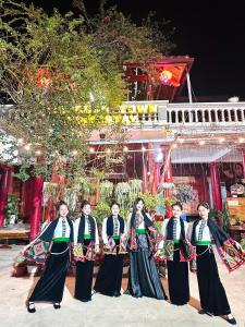 a group of women in traditional dress standing in front of a building at Moc Chau Town - Homestay in Mộc Châu +16 photos