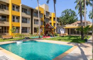 a swimming pool in front of a building with a playground at Goa stays in Anjuna