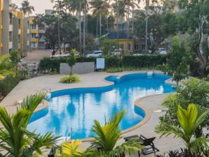a pool in a resort with palm trees and buildings at Goa stays in Anjuna