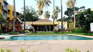a swimming pool in front of a building with palm trees at Goa stays in Anjuna