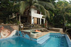 a house with a painting on the side of a swimming pool at Cocovana Beach Resort in Busuanga